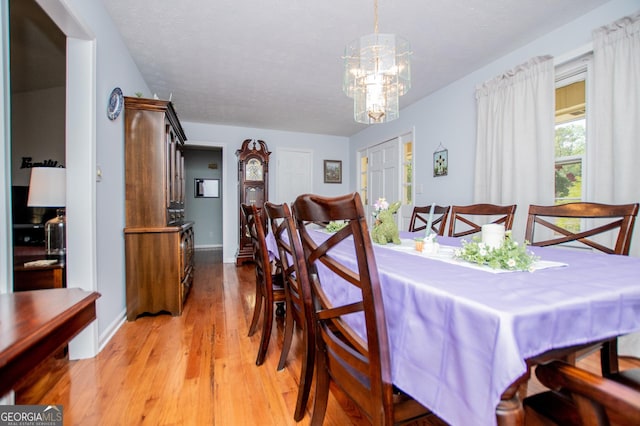 dining space with light wood-type flooring, baseboards, and a notable chandelier
