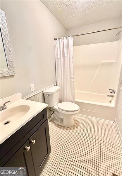 1836 Rainbow Ln, Powder Springs, GA 30127 - bathroom featuring toilet, vanity, shower / tub combo with curtain, a textured ceiling, and tile patterned floors