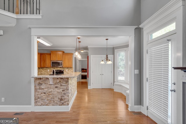 kitchen featuring visible vents, ornamental molding, stainless steel microwave, decorative light fixtures, and decorative backsplash