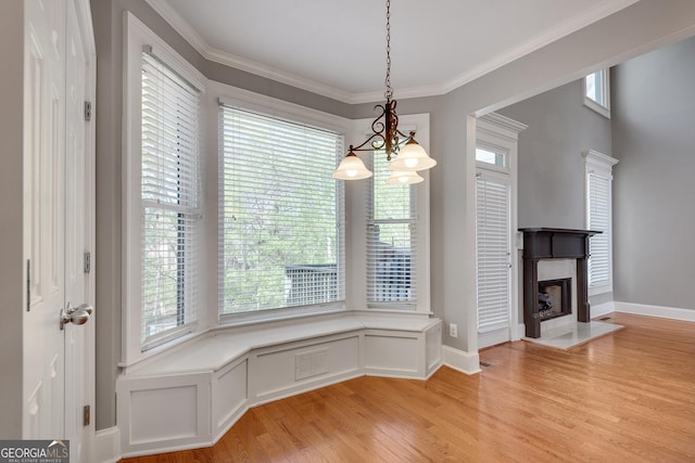 unfurnished dining area featuring an inviting chandelier, a high end fireplace, visible vents, ornamental molding, and light wood-style flooring
