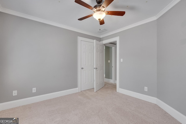 empty room featuring a ceiling fan, baseboards, carpet floors, and crown molding