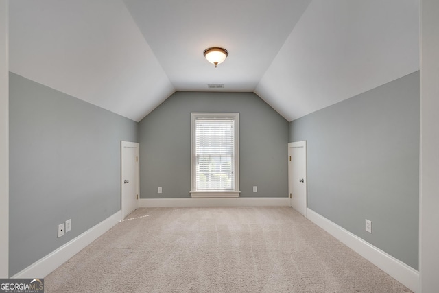 additional living space with lofted ceiling, visible vents, baseboards, and light carpet