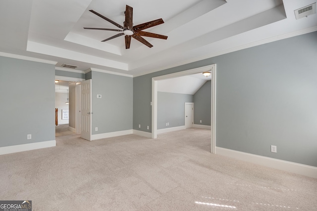 spare room with a ceiling fan, visible vents, a raised ceiling, and light colored carpet
