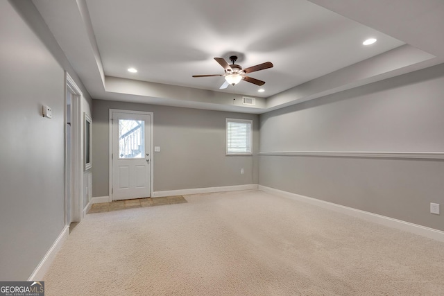 foyer entrance with ceiling fan, light carpet, a raised ceiling, baseboards, and recessed lighting