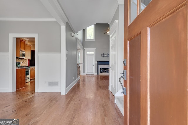 entrance foyer with light wood finished floors, visible vents, high vaulted ceiling, and crown molding