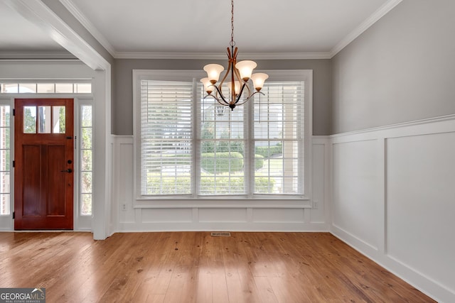 entryway with hardwood / wood-style floors, a decorative wall, and an inviting chandelier