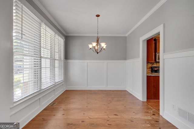 unfurnished dining area with visible vents, a wealth of natural light, a chandelier, and crown molding