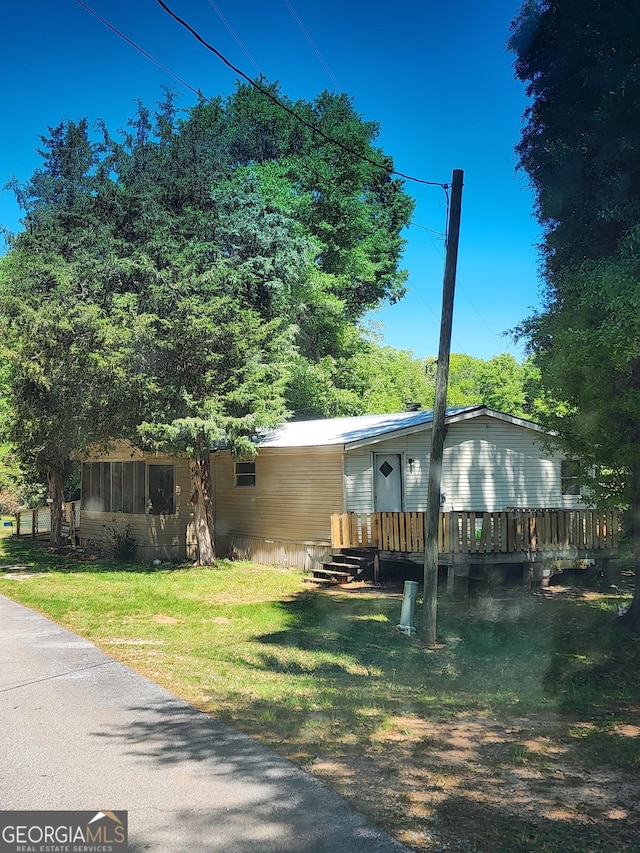 manufactured / mobile home featuring a wooden deck and a front lawn