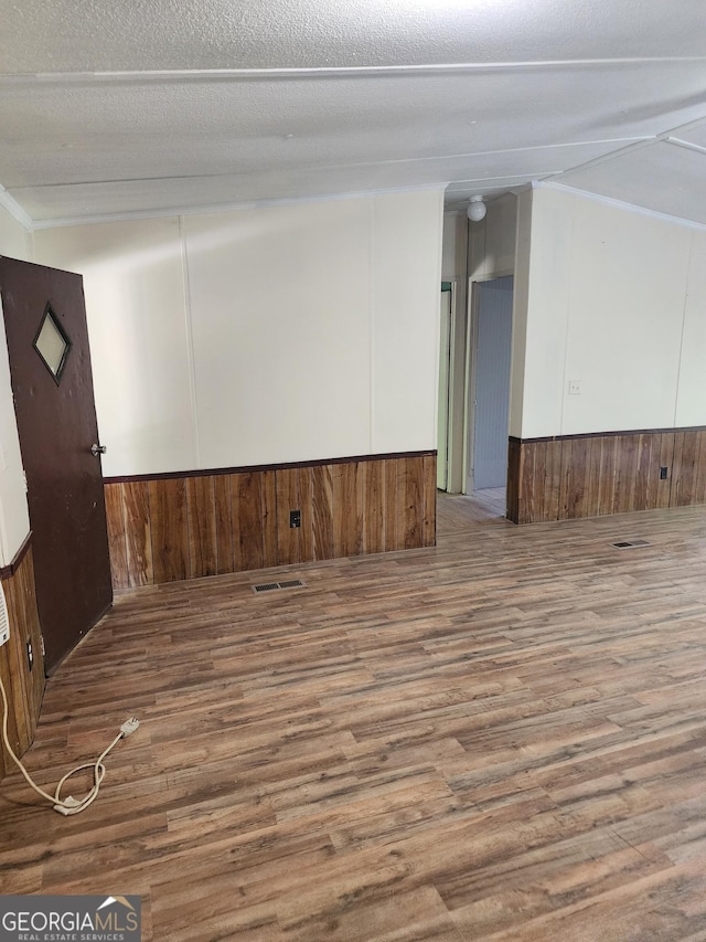 empty room with wooden walls, wood finished floors, and visible vents