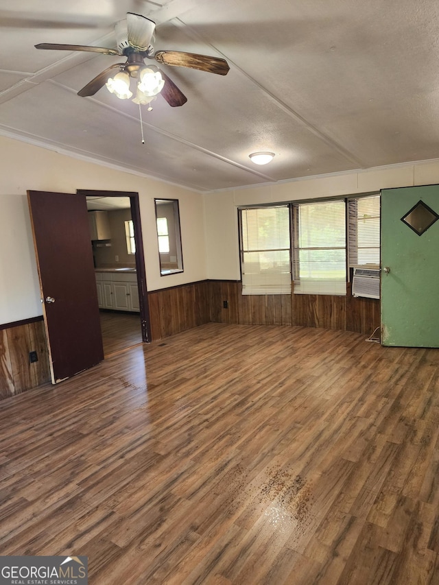 unfurnished room with wooden walls, wood finished floors, and a wainscoted wall