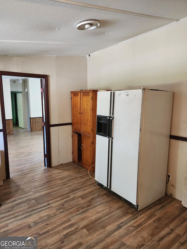 kitchen with brown cabinetry, white fridge with ice dispenser, a textured ceiling, and dark wood finished floors