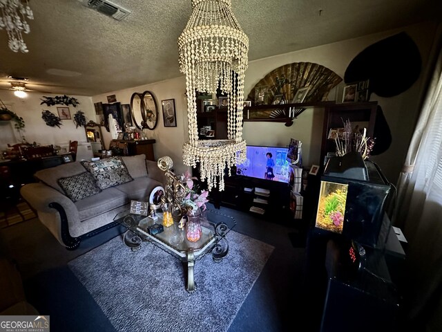 living area featuring a textured ceiling, visible vents, and ceiling fan with notable chandelier