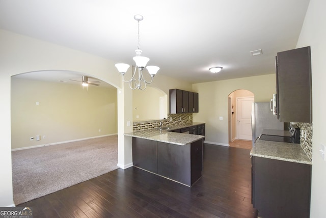 kitchen with electric range, arched walkways, tasteful backsplash, and dark brown cabinets
