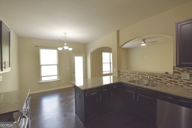 kitchen with dishwasher, backsplash, arched walkways, and a sink