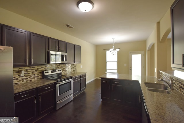 kitchen featuring light stone counters, a sink, decorative backsplash, appliances with stainless steel finishes, and visible vents