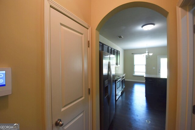 hallway featuring baseboards, visible vents, arched walkways, and dark wood-style flooring