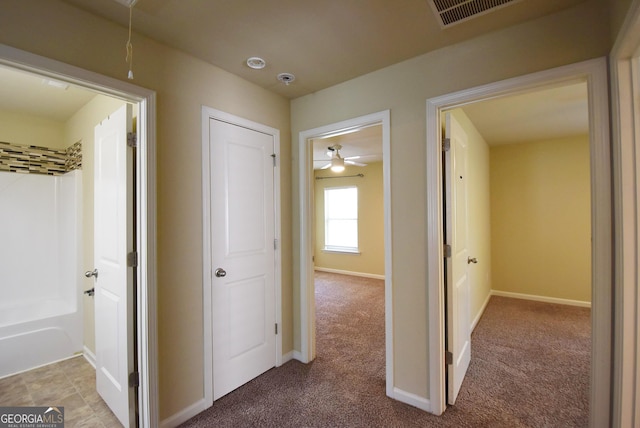 hallway with attic access, baseboards, visible vents, and carpet