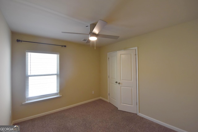 carpeted empty room featuring visible vents, baseboards, and ceiling fan