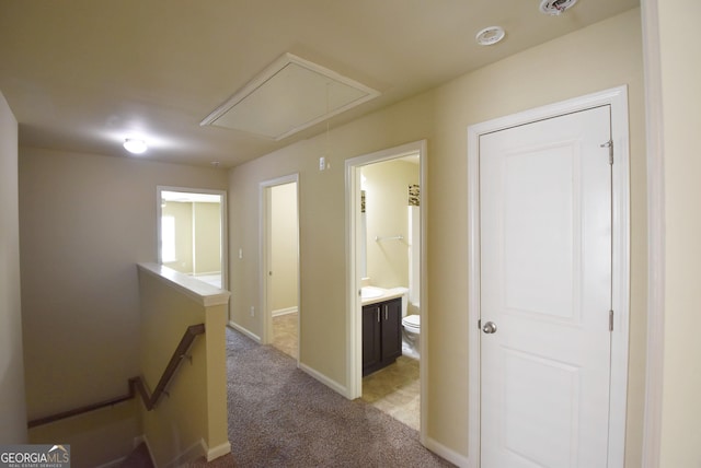 hall featuring attic access, baseboards, an upstairs landing, and light colored carpet