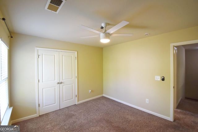 unfurnished bedroom featuring carpet flooring, baseboards, visible vents, a closet, and ceiling fan