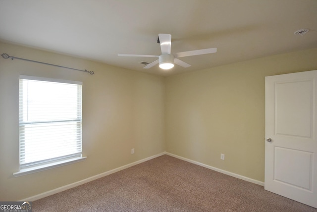 carpeted empty room featuring baseboards, visible vents, and ceiling fan