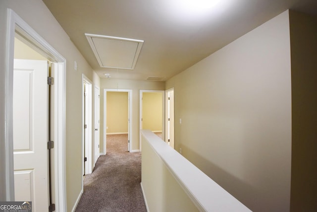 hall featuring attic access and dark carpet