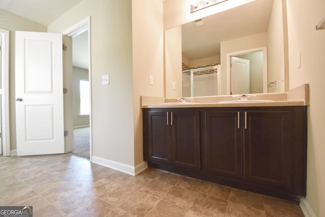 full bathroom with baseboards, a sink, a shower, and double vanity