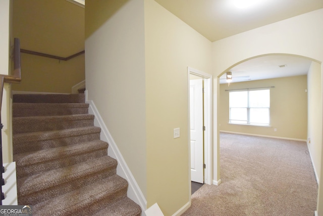 stairs featuring arched walkways, carpet flooring, and baseboards