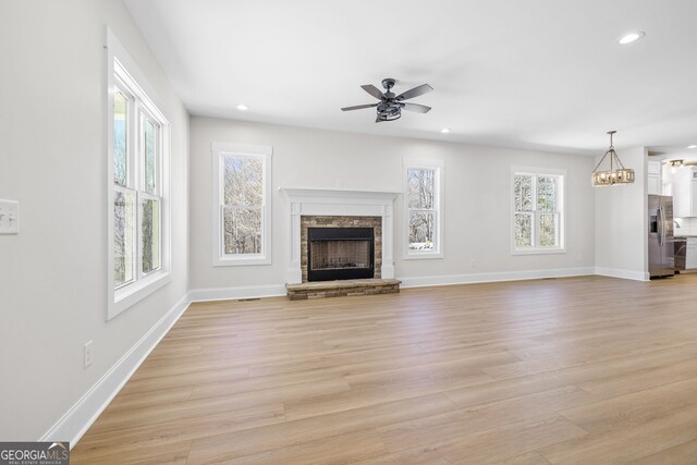 405 Roper Dr, Clarkesville, GA 30523 - unfurnished living room with light wood-type flooring, recessed lighting, a fireplace with raised hearth, and ceiling fan with notable chandelier