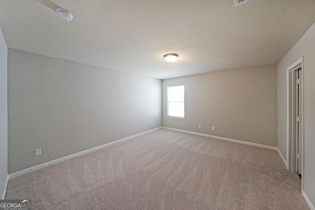 spare room featuring light carpet and baseboards