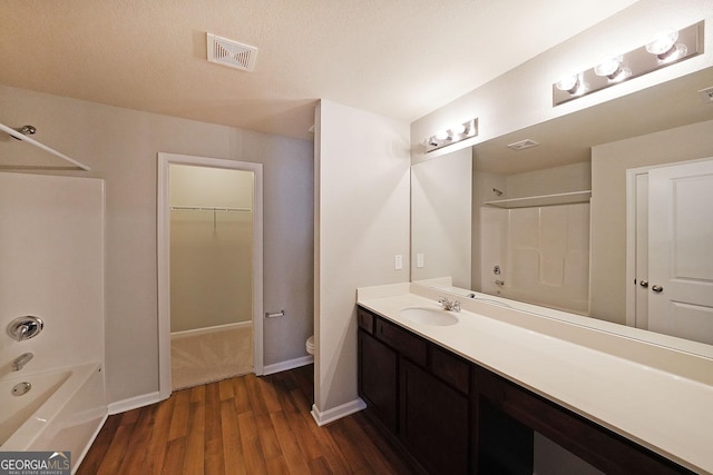 bathroom featuring toilet, shower / bathtub combination, visible vents, wood finished floors, and vanity