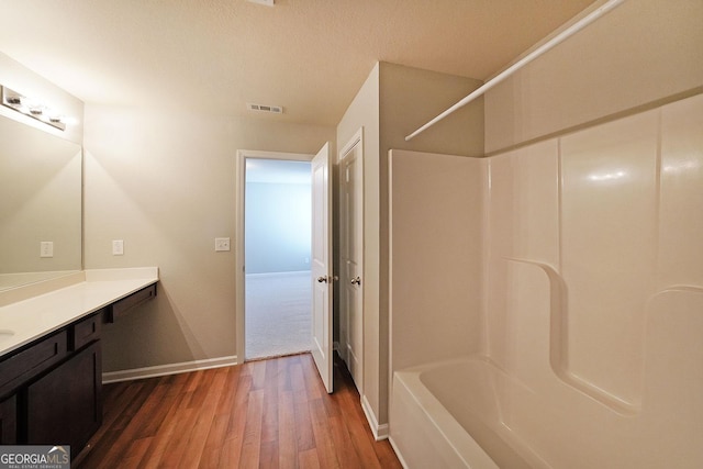 bathroom featuring wood finished floors, visible vents, vanity, baseboards, and shower / tub combination