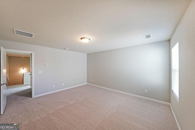 empty room with baseboards, visible vents, and carpet flooring