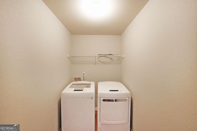 laundry area featuring separate washer and dryer, a textured wall, and laundry area
