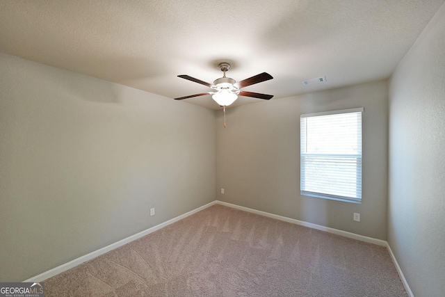 empty room featuring baseboards, visible vents, a ceiling fan, and light colored carpet