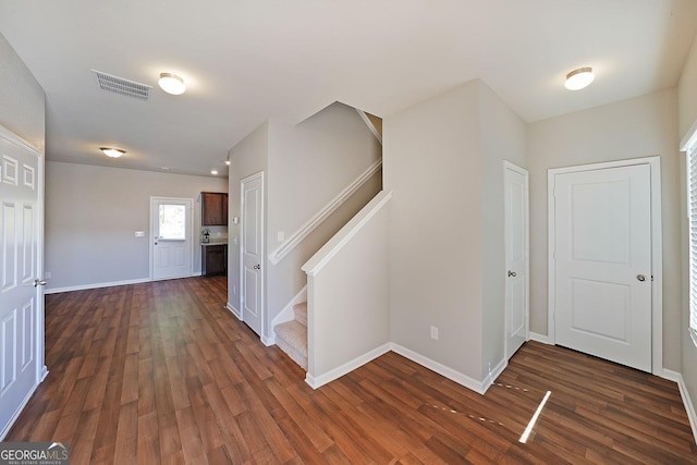 entryway with dark wood finished floors, baseboards, stairs, and visible vents