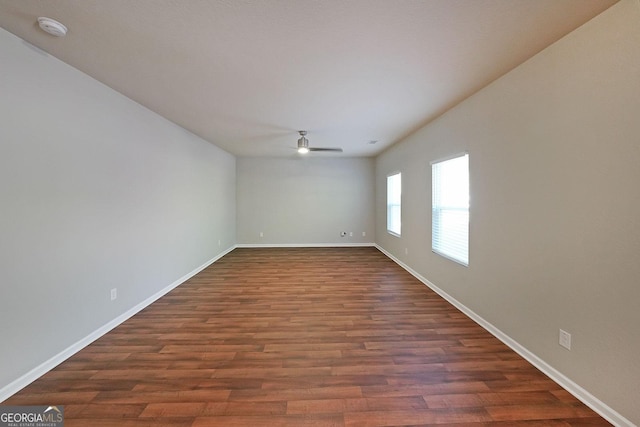 spare room with dark wood-style flooring, baseboards, and ceiling fan