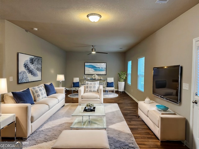 living area with ceiling fan, baseboards, wood finished floors, and a textured ceiling