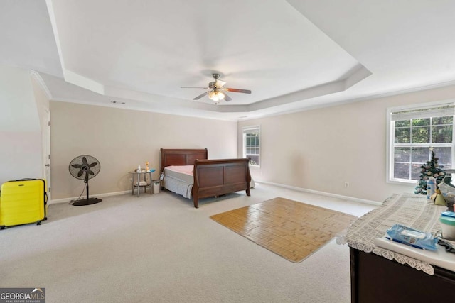 bedroom featuring baseboards, light colored carpet, a raised ceiling, and multiple windows