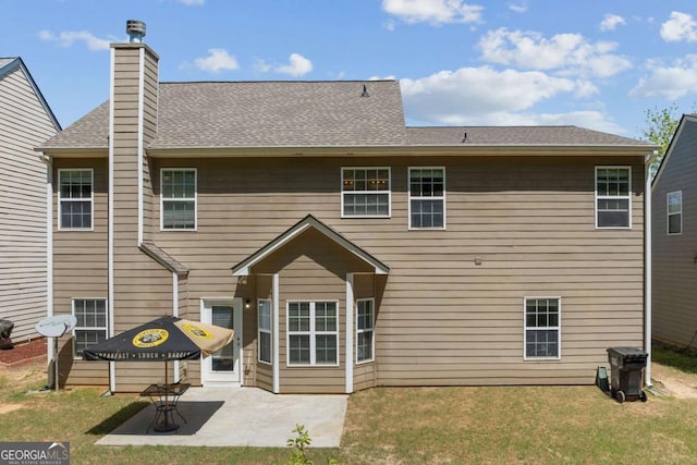 rear view of property featuring a lawn, a chimney, a patio, and a shingled roof
