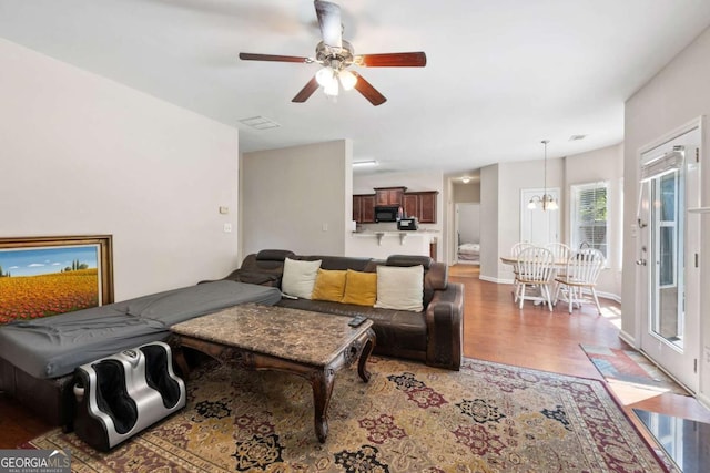 living room with light wood-style floors and ceiling fan with notable chandelier