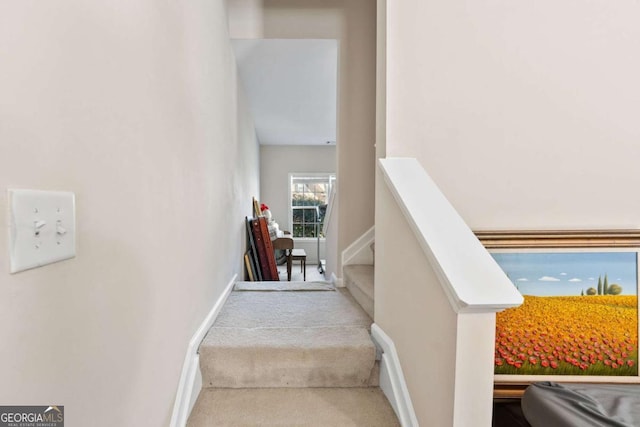 stairway with baseboards and carpet flooring