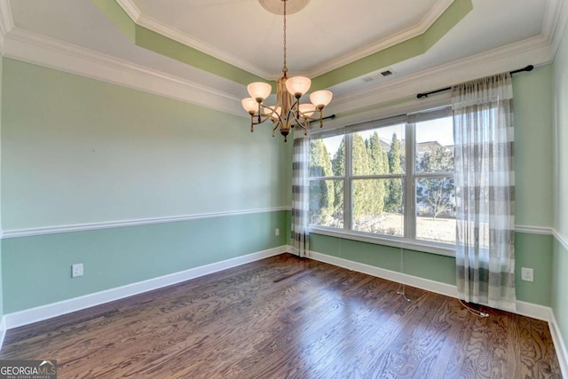 spare room with a chandelier, baseboards, wood finished floors, and a tray ceiling