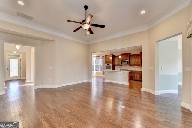 unfurnished living room with wood finished floors, visible vents, a ceiling fan, and a wealth of natural light