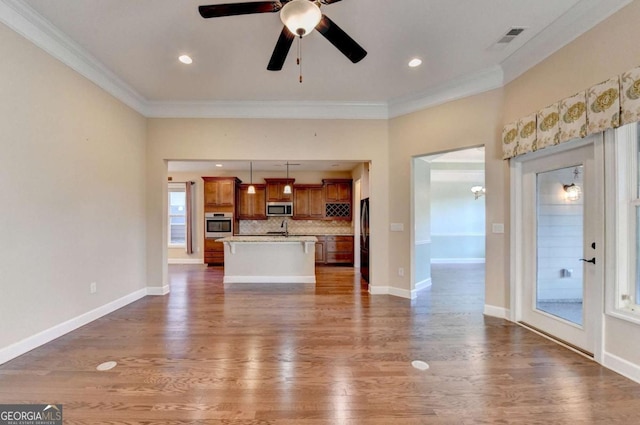unfurnished living room with crown molding, ceiling fan, dark wood finished floors, baseboards, and visible vents