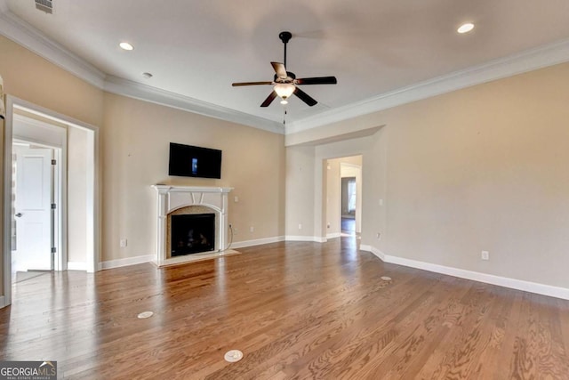 unfurnished living room featuring a fireplace, wood finished floors, crown molding, and ceiling fan