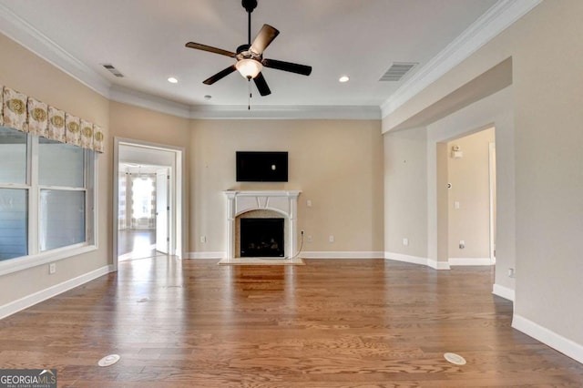 unfurnished living room with a ceiling fan, crown molding, wood finished floors, a fireplace, and visible vents
