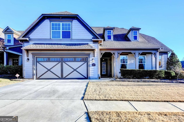 view of front facade with an attached garage, a shingled roof, and concrete driveway