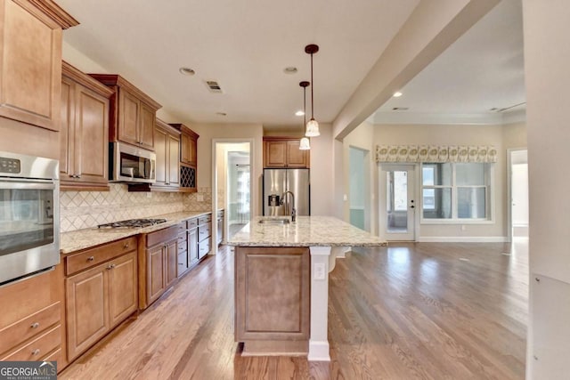kitchen with visible vents, light stone countertops, light wood-style flooring, tasteful backsplash, and appliances with stainless steel finishes