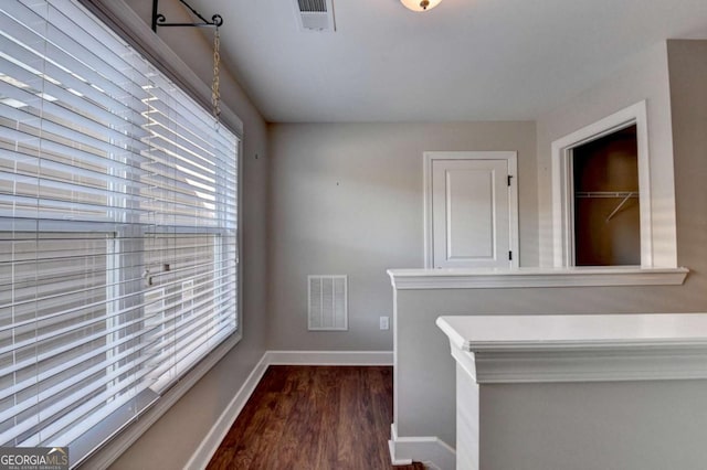 hall featuring baseboards, visible vents, and dark wood-style floors